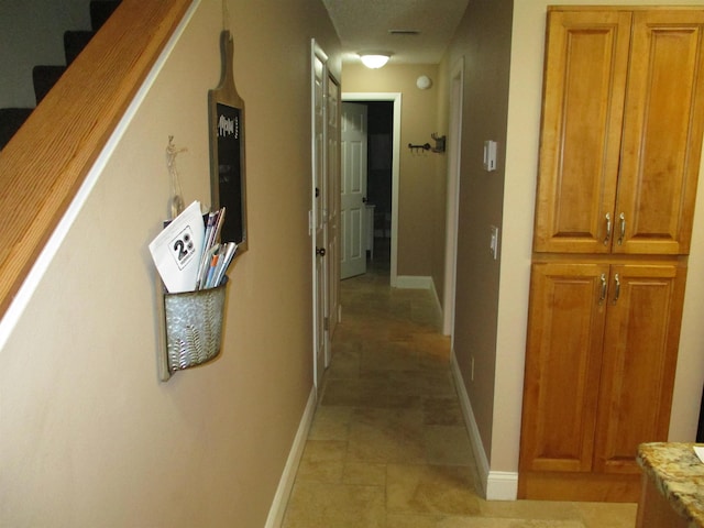 corridor featuring stairway and baseboards