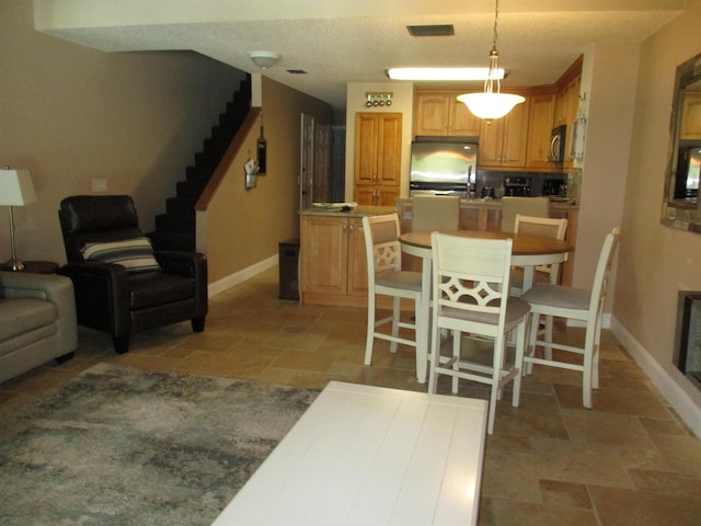 kitchen featuring baseboards, appliances with stainless steel finishes, decorative light fixtures, and a center island