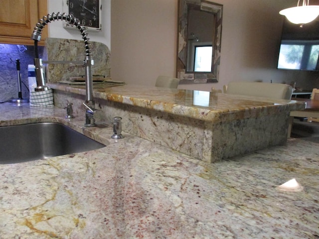 kitchen featuring light stone countertops, tasteful backsplash, and a sink