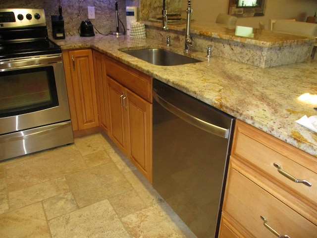 kitchen with a sink, appliances with stainless steel finishes, backsplash, light stone countertops, and brown cabinetry