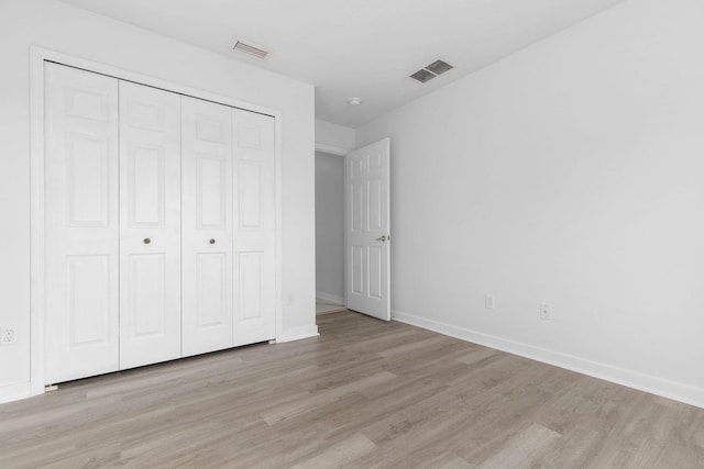 unfurnished bedroom with light wood-style floors, visible vents, a closet, and baseboards