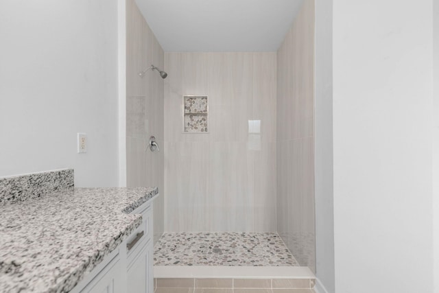 full bathroom featuring tiled shower and vanity