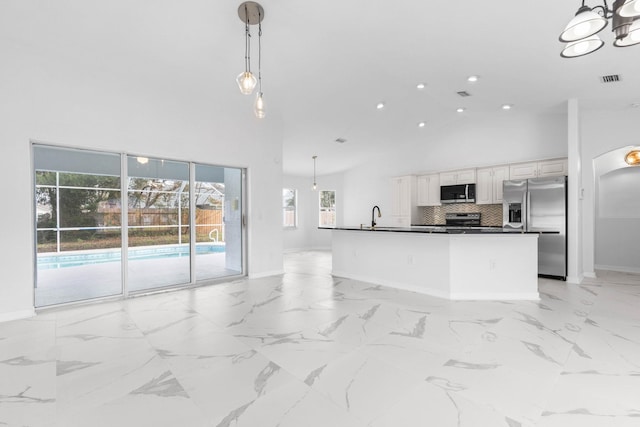 kitchen featuring dark countertops, decorative backsplash, stainless steel appliances, high vaulted ceiling, and a sink