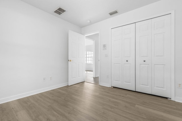 unfurnished bedroom with visible vents, baseboards, and wood finished floors