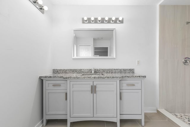 bathroom with vanity, tile patterned floors, baseboards, and tiled shower