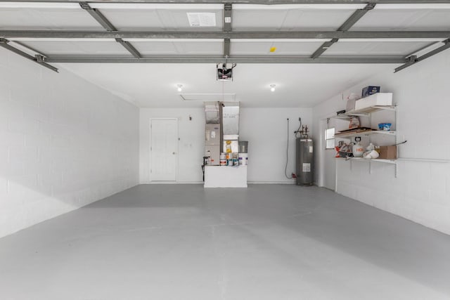 garage with heating unit, a garage door opener, electric water heater, and concrete block wall