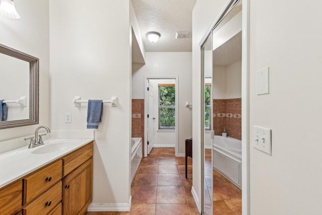 bathroom with tile patterned flooring, vanity, a bath, and a textured ceiling