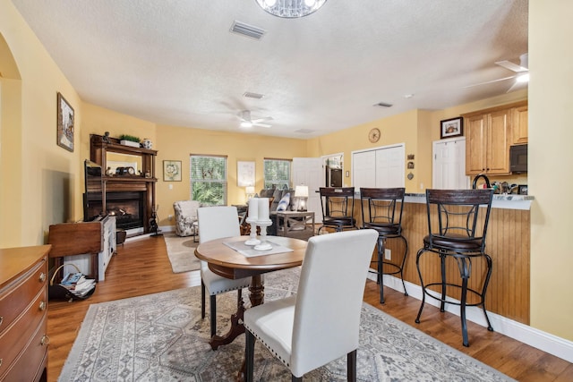 dining room featuring ceiling fan, light hardwood / wood-style floors, and a textured ceiling