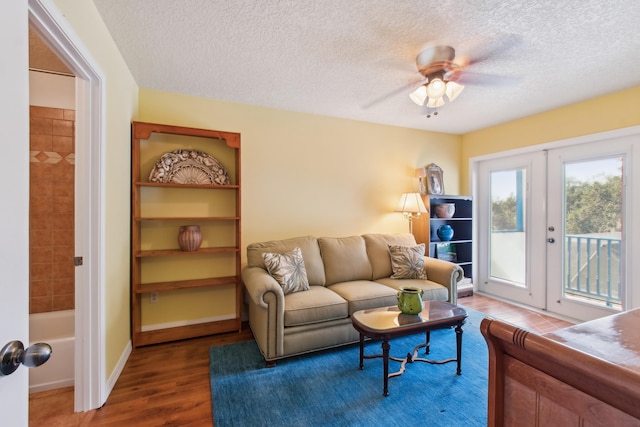 living room featuring ceiling fan, dark wood-type flooring, a textured ceiling, and french doors