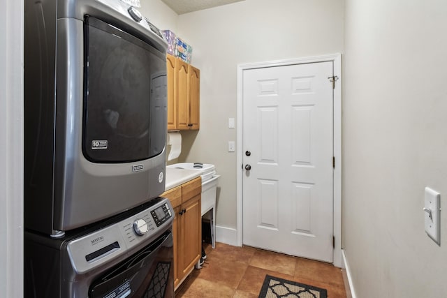 washroom with light tile patterned flooring, cabinets, and stacked washer and clothes dryer