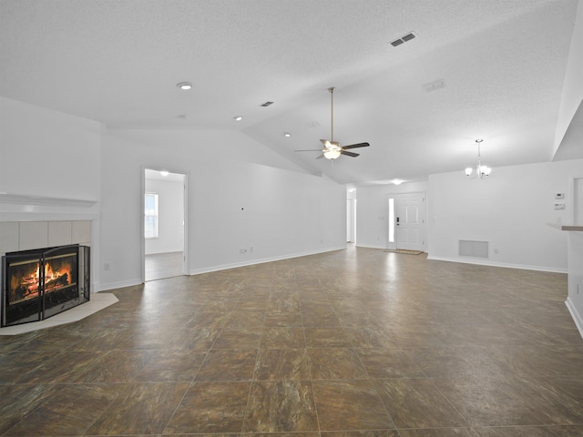 unfurnished living room featuring vaulted ceiling, a textured ceiling, ceiling fan with notable chandelier, and a tile fireplace