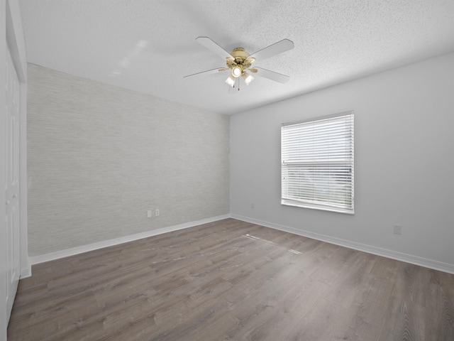 unfurnished room featuring ceiling fan, a textured ceiling, and dark hardwood / wood-style flooring