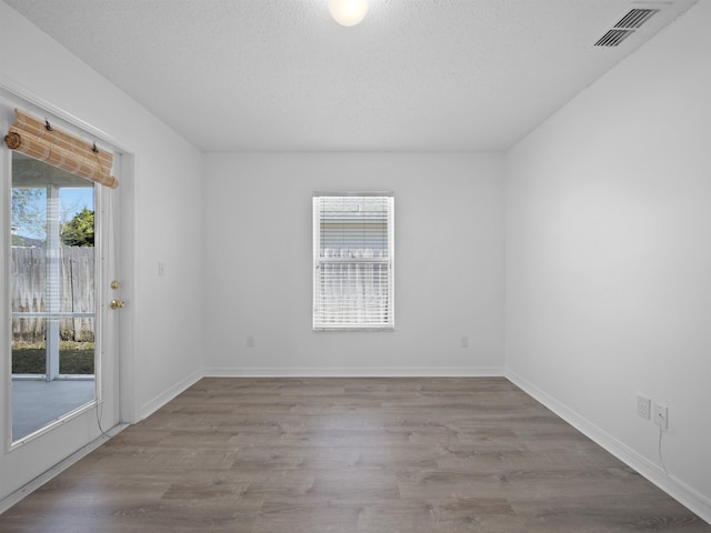 spare room with light hardwood / wood-style floors, plenty of natural light, and a textured ceiling