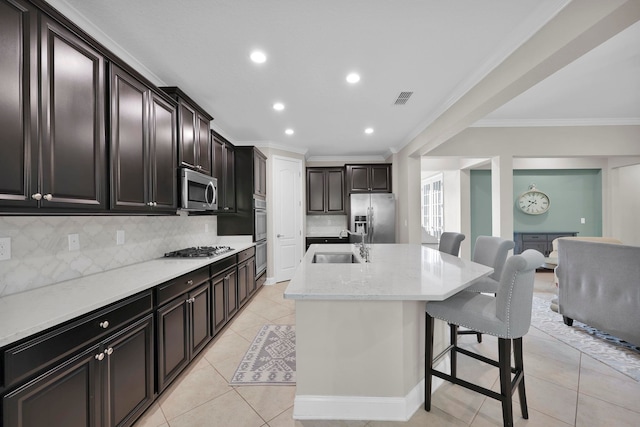 2790 Las Calinas Blvd, Saint Augustine, FL 32095 - kitchen featuring appliances with stainless steel finishes, crown molding, a breakfast bar area, decorative backsplash, and a kitchen island with sink