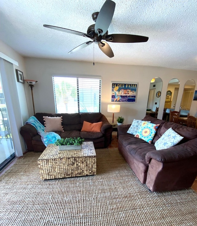 carpeted living room with a textured ceiling and ceiling fan