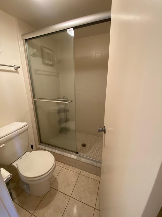 bathroom with tile patterned floors, a shower with door, and toilet