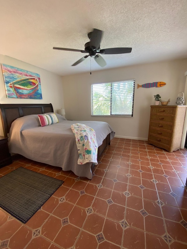 tiled bedroom with ceiling fan and a textured ceiling