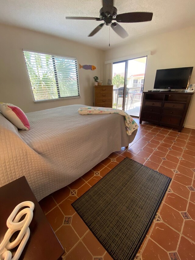 bedroom featuring access to exterior, a textured ceiling, ceiling fan, and tile patterned flooring