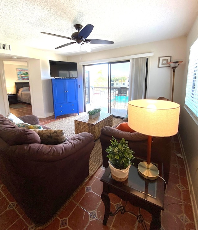 tiled living room featuring ceiling fan and a textured ceiling