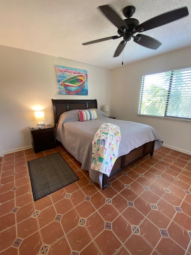 tiled bedroom featuring ceiling fan and a textured ceiling