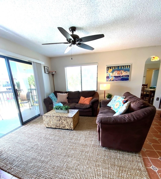 tiled living room with ceiling fan and a textured ceiling