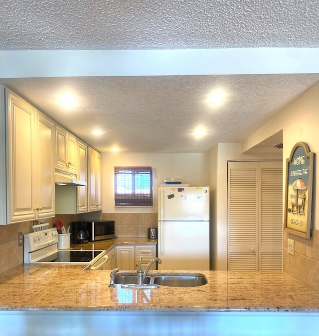 kitchen featuring kitchen peninsula, a textured ceiling, white appliances, and sink