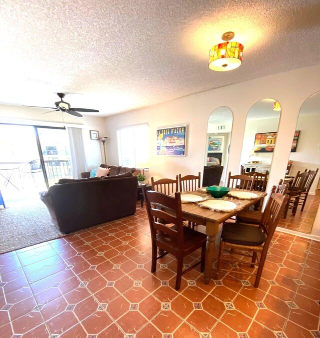 tiled dining area with ceiling fan and a textured ceiling