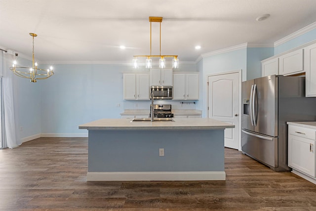 kitchen with stainless steel appliances, light countertops, decorative light fixtures, and an island with sink