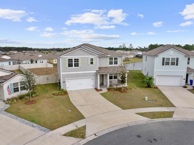 traditional-style house with an attached garage, a residential view, a front lawn, and concrete driveway