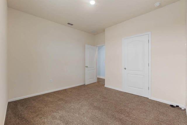 carpeted empty room with visible vents and baseboards