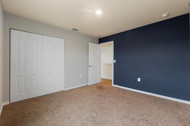 unfurnished bedroom featuring carpet, a closet, visible vents, and baseboards