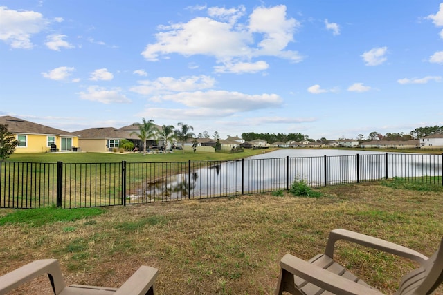 view of yard with a residential view, a water view, and a fenced backyard