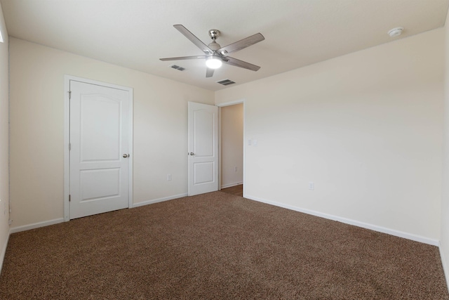 unfurnished bedroom featuring dark colored carpet, a ceiling fan, visible vents, and baseboards