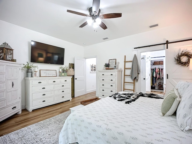 8975 Reid Packing House Rd, Hastings, FL 32145 - bedroom with a barn door, light wood-type flooring, a walk in closet, and a ceiling fan