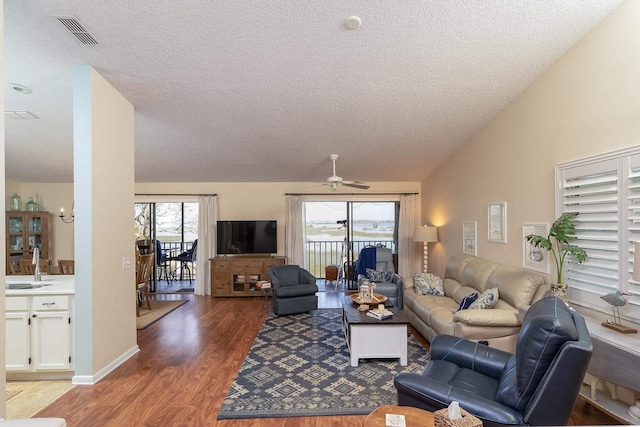 living room with a healthy amount of sunlight, lofted ceiling, sink, and dark hardwood / wood-style flooring