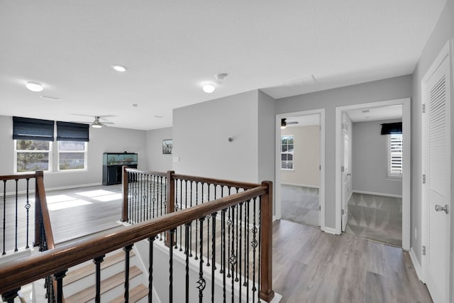 hall featuring light wood-type flooring, a textured ceiling, and a healthy amount of sunlight