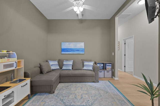 living room featuring sink, ceiling fan, and light wood-type flooring