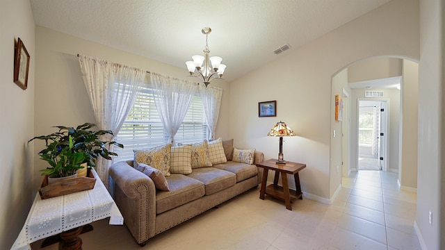 living room with a textured ceiling, light tile patterned floors, lofted ceiling, and a notable chandelier