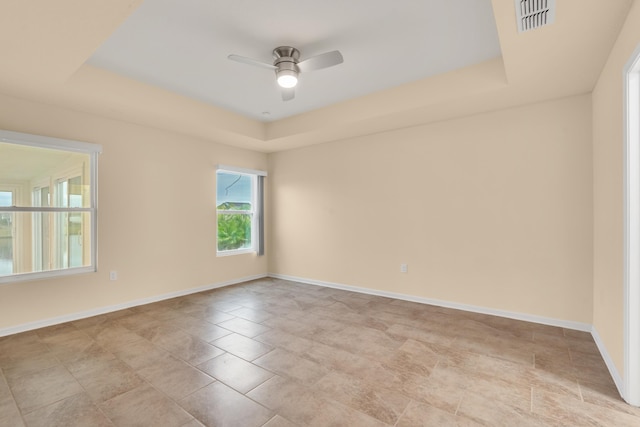 empty room featuring a raised ceiling and ceiling fan