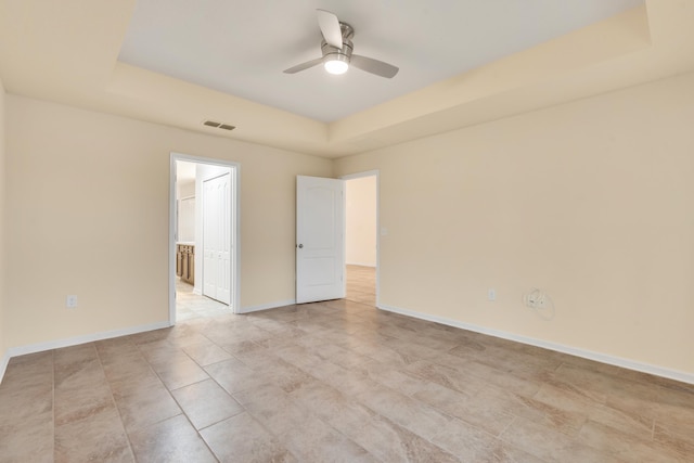 unfurnished room featuring a raised ceiling and ceiling fan