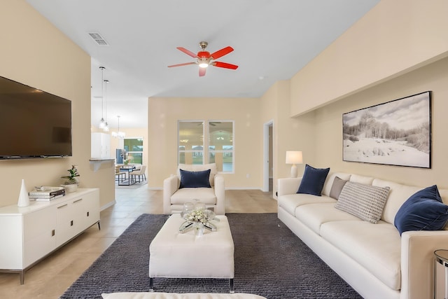 tiled living room featuring ceiling fan with notable chandelier