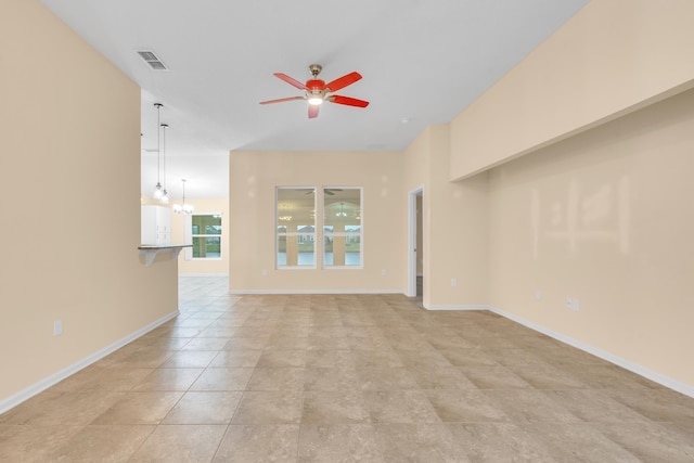 unfurnished living room with ceiling fan with notable chandelier and light tile patterned floors