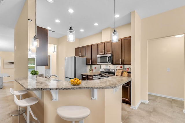 kitchen featuring stainless steel appliances, decorative light fixtures, a kitchen breakfast bar, kitchen peninsula, and light stone countertops