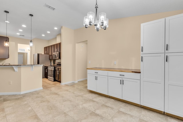 kitchen with stainless steel appliances, a chandelier, white cabinets, and pendant lighting