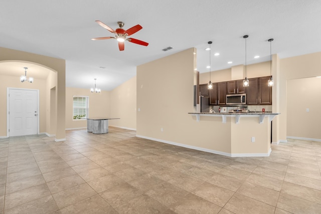 kitchen featuring stainless steel appliances, a kitchen bar, ceiling fan with notable chandelier, dark brown cabinets, and pendant lighting