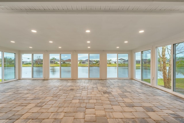 unfurnished sunroom with a water view and beamed ceiling