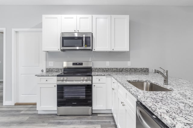 kitchen with white cabinetry, appliances with stainless steel finishes, sink, and light hardwood / wood-style flooring