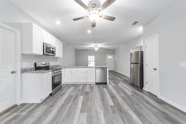 kitchen with white cabinets, ceiling fan, light stone counters, stainless steel appliances, and light hardwood / wood-style floors