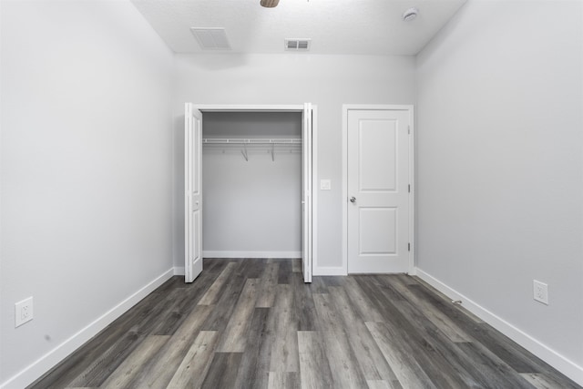 unfurnished bedroom featuring ceiling fan, dark wood-type flooring, a textured ceiling, and a closet