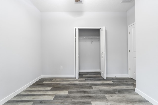 unfurnished bedroom featuring dark hardwood / wood-style flooring and a closet